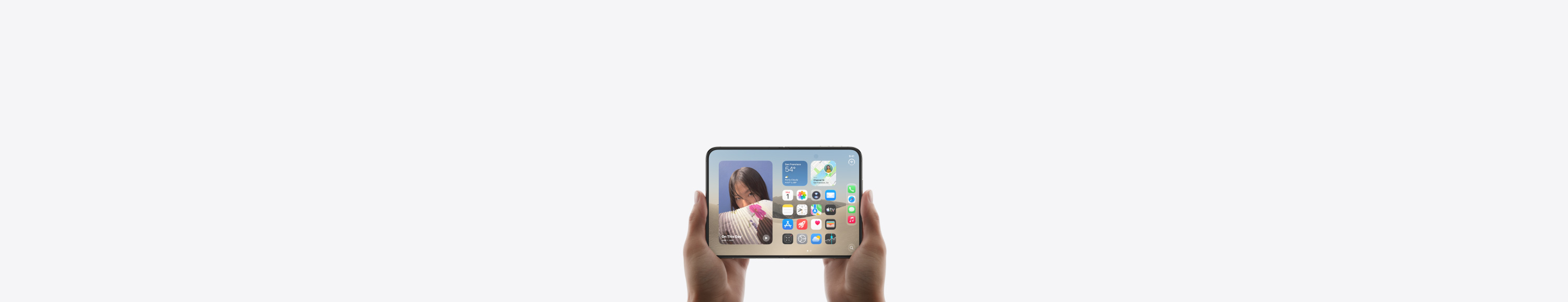 Két kézben tartott, fekvő tájolású, kinyitott iPhone Duo, a belső kijelzőn a főképernyő látható.
